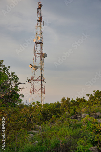 This unique photo shows a transmitter and telephone pole in Thailand standing on top of a mountain in the middle of nature at sunset