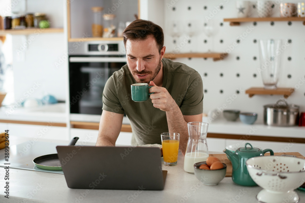 Young man eating breakfast and reading the news online. Handsome man enjoying at home Young man eating breakfast and reading the news online. Handsome man enjoying at home