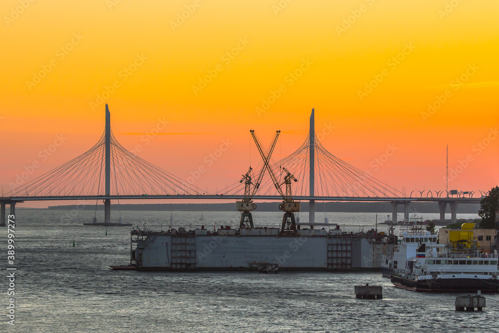 cable-stayed bridge over the river and floating dock at sunset