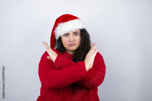 Young beautiful woman wearing a Santa hat over white background Rejection expression crossing arms doing negative sign  angry face