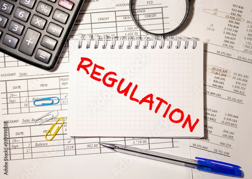 The words REGULATION is written in black letters on the yellow paper for notes