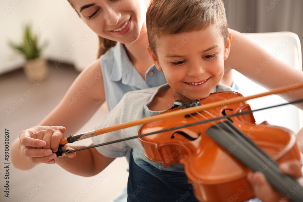 Young woman teaching little boy to play violin indoors Young woman teaching little boy to play violin indoors