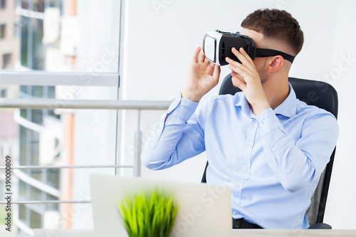 Young man wearing virtual reality glasses in modern office.
