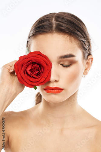 charming brunette girl with makeup on her face and a red rose in her hand