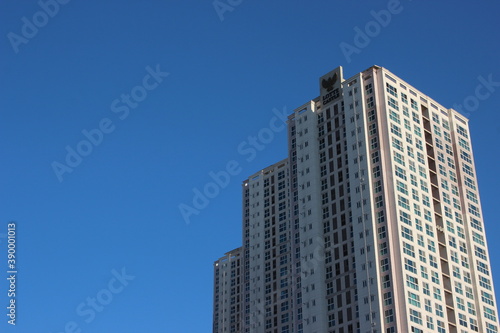 The wide-angle view of a skyscraper commercial building with blue sky on sunny day. © Photochowk