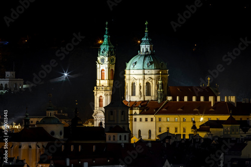  illuminated church of St. Nicholas from the 17th century and light from street lights at night in the center of the old town of Prague