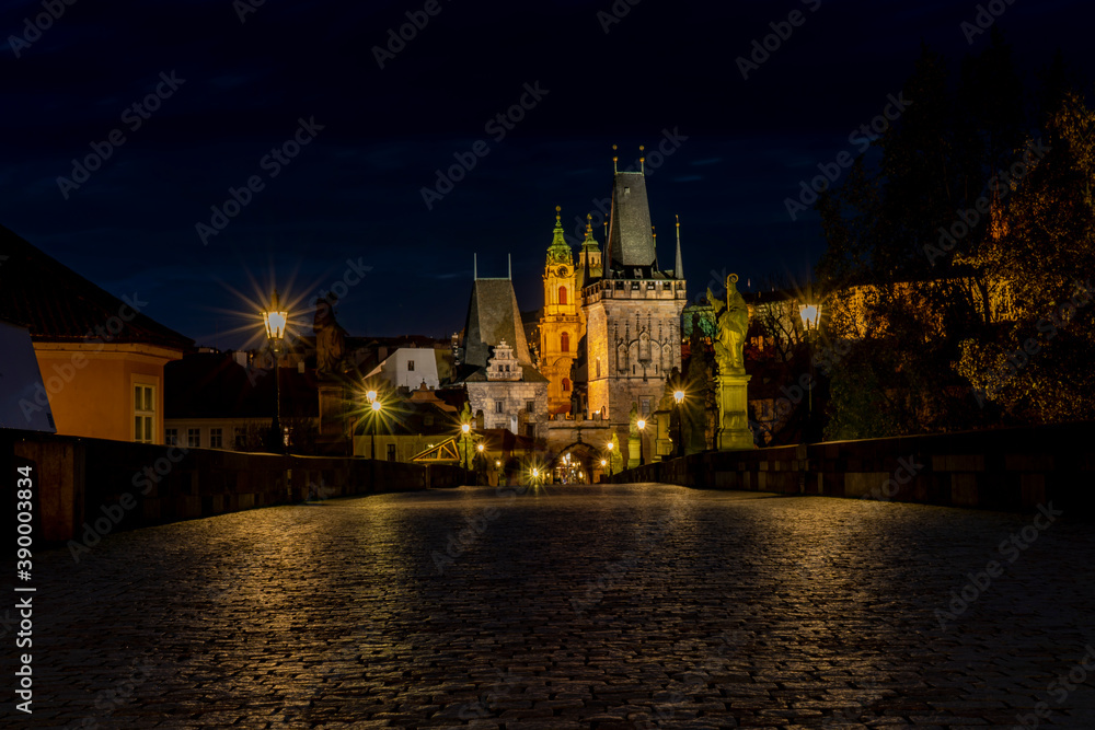 
old paved sidewalk with paving stones in memory of Charles Bridge from the 14th century in the center of Prague and in the background the old bridge tower at night in the Czech Republic