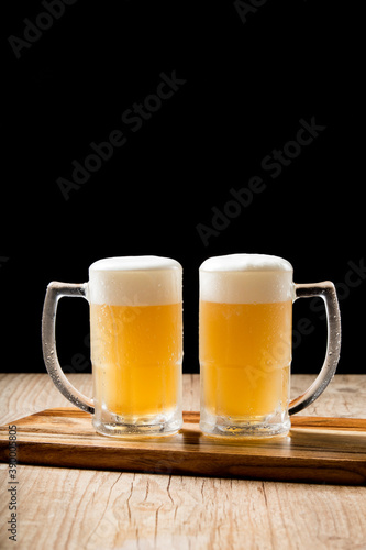 Two draft mugs beer on woden table and black background