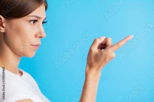 Young woman holding contact lens on finger.