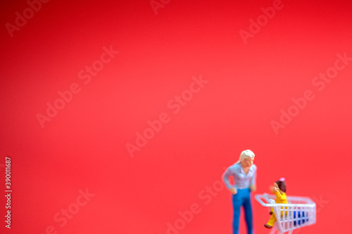 Miniature people with shopping cart in shopping mall with red background. Holiday shopping concept. banner size