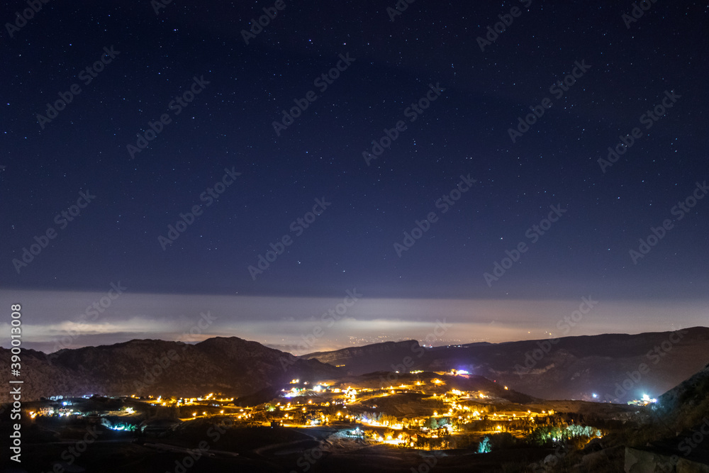 Fototapeta premium sky full of stars above a town and a mountain range