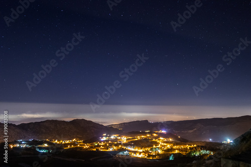 sky full of stars above a town and a mountain range