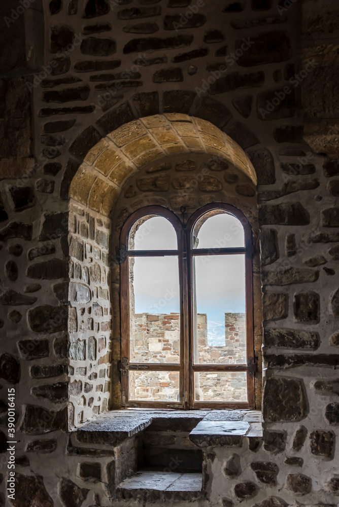 View of the window in the thick stone wall from inside the tower of Genoese fortress of 14th century in the Sudak bay on the Peninsula of Crimea