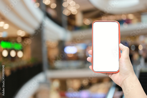 Hand of a man holding smartphone device in the Shopping mall background.