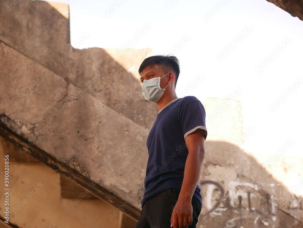 Handsome Indonesian young man wearing face mask in abandoned buildings. Portrait of confident Indonesian young man wearing face mask during coronavirus