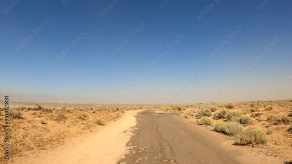Driving down a desolate Mojave Desert road covered with sand by wind and storms - point of view Driving down a desolate Mojave Desert road covered with sand by wind and storms - point of view