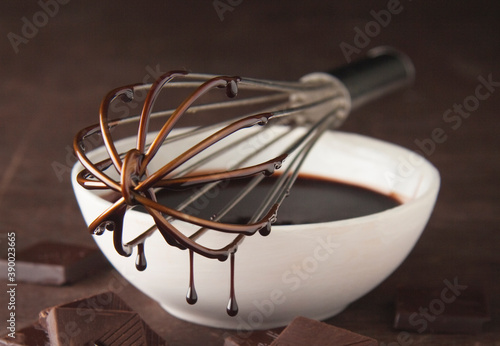 whisk in a bowl dripping with chocolate sauce