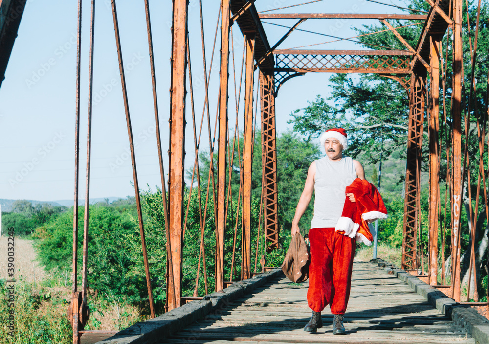 man dressed as santa claus walking on an old bridge, christmas concept, man works as santa claus man dressed as santa claus walking on an old bridge, christmas concept, man works as santa claus