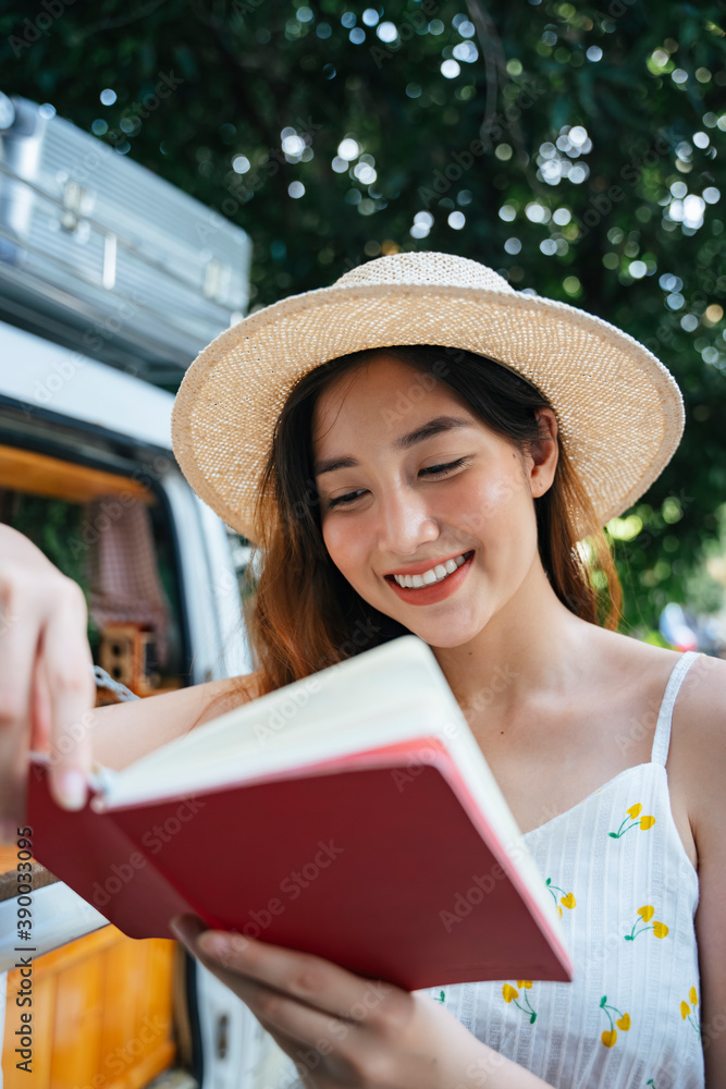 Beautiful asian woman wear hat reading a book in garden.