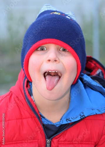 Retrato de un niño que saca la lengua burlándose con gorro de lana photo
