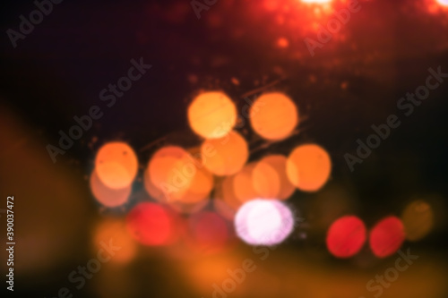 Abstract bokeh blur background by rain drops on glass window at night in the city