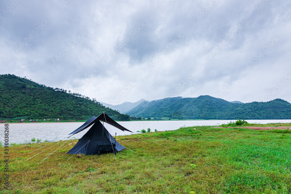 Nature tourism concept with black tent By the lake, there are valleys and clouds in the rainy season.