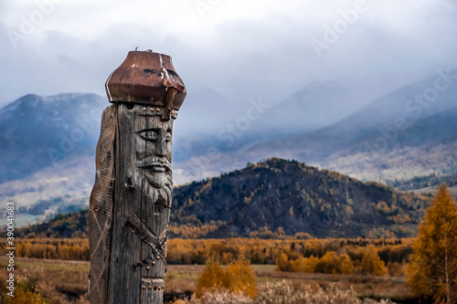 Wooden totem pillar on mountains background in autumn. Orthodox old believers totem. Religious symbol.