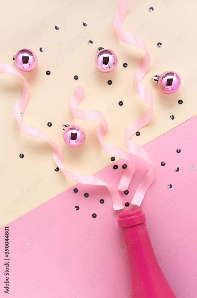 Creative concept holiday celebration photo of christmas toys balls ribbon decoration with champagne bottle drink on pink yellow background. Creative concept holiday celebration photo of christmas toys balls ribbon decoration with champagne bottle drink on pink yellow background.