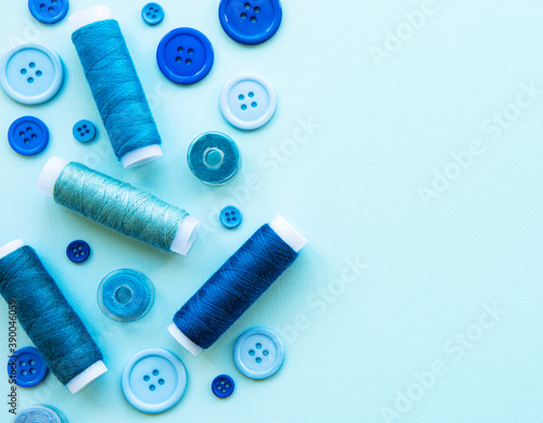 Spools of thread and buttons in blue tones on a blue background