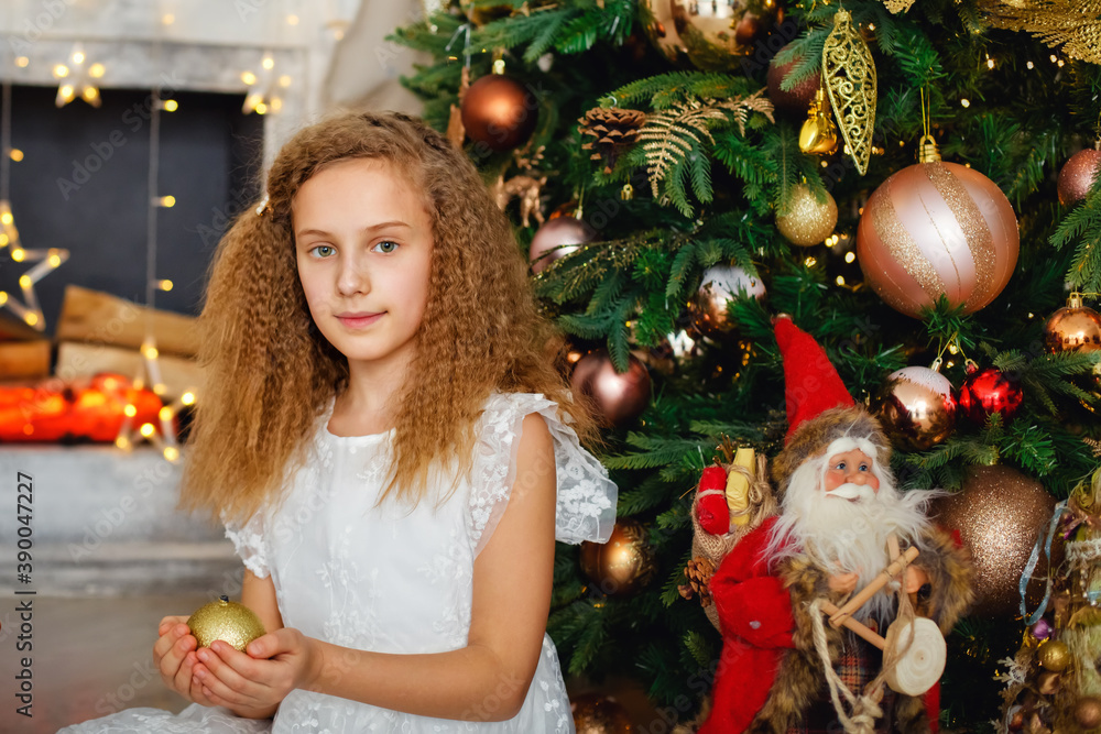 The concept of New year and Christmas. Portrait of a pretty girl by the fire at Christmas. On Christmas night, a little girl is waiting for Santa Claus. A little girl dreams of Christmas.