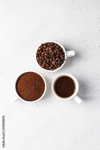 Coffee beans, ground and espresso in three white cups
