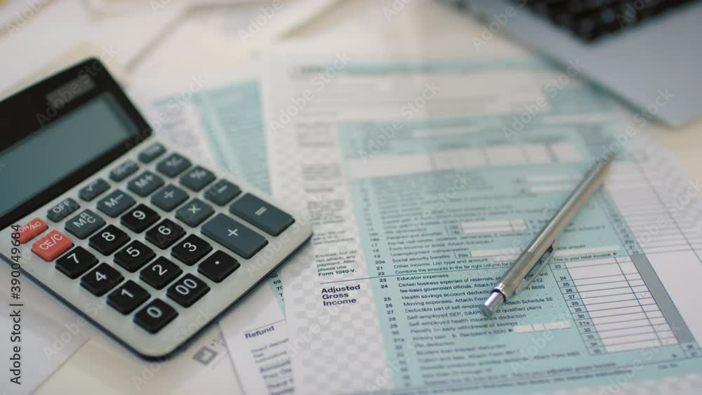 From above flat lay stab closeup of printed tax return form with calculator lying at coffee table From above flat lay stab closeup of printed tax return form with calculator lying at coffee table
