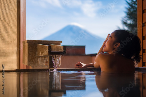 Beautiful woman enjoy onsen (mineral hot bath) in morning and seeing view of Fuji mountain in japan
