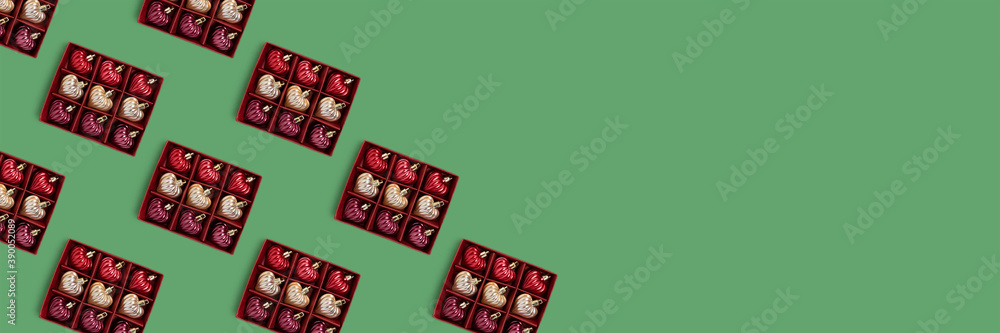 Fototapeta premium Banner with frame made of boxes with New Year decorations pattern on a green background. Holidays concept with copy space.