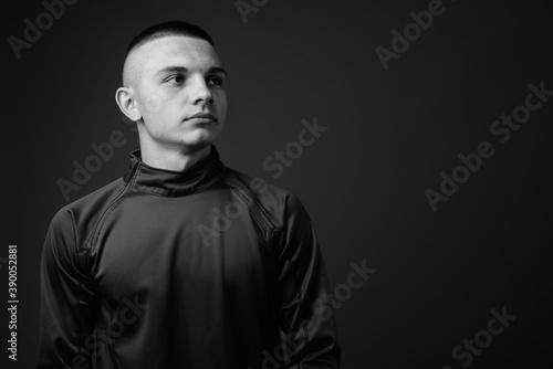 Studio shot of young handsome man with short hair against gray background