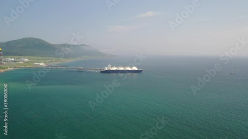 day, filming from a quadrocopter in a spiral, on the coast of the Okhotsk sea at the pier of a liquefied natural gas plant in the city of Korsakov there is a gas tanker, several tugboats are nearby photo