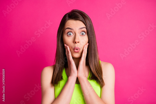 Portrait of surprised nice brunette long straight hair young lady hands cheeks wear lime top isolated on vivid pink background