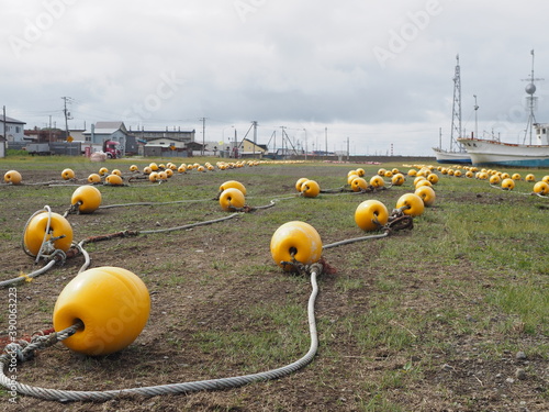 Yellow buoys and beacons on seaside harbour in fishing village on cloudy day on Hokkaido island, northern Japan