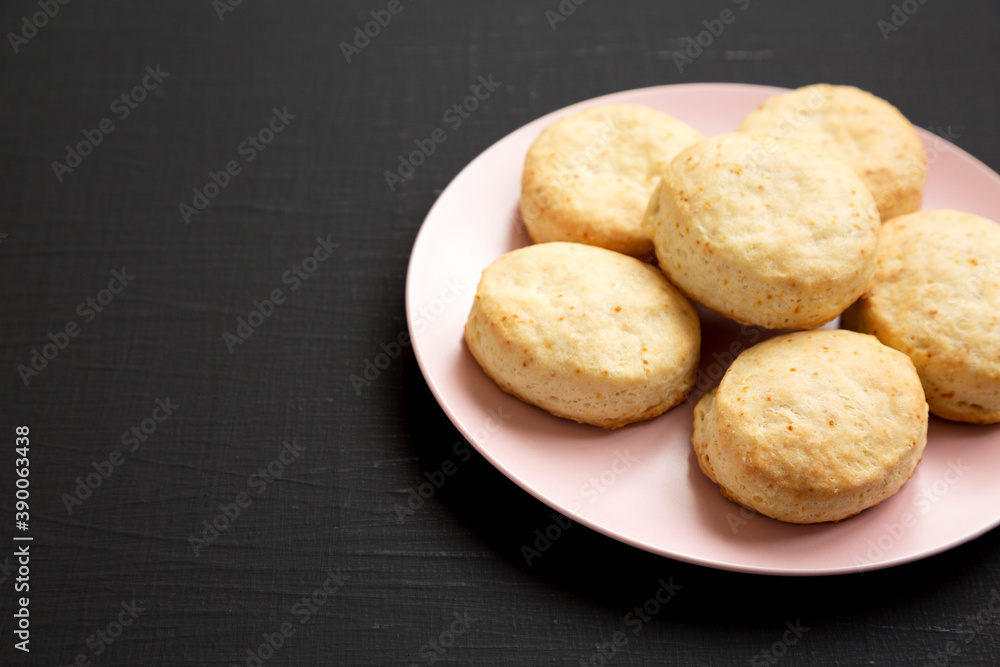 Homemade Flaky Buttermilk Biscuits on a pink plate on a black surface, side view. Copy space. Homemade Flaky Buttermilk Biscuits on a pink plate on a black surface, side view. Copy space.