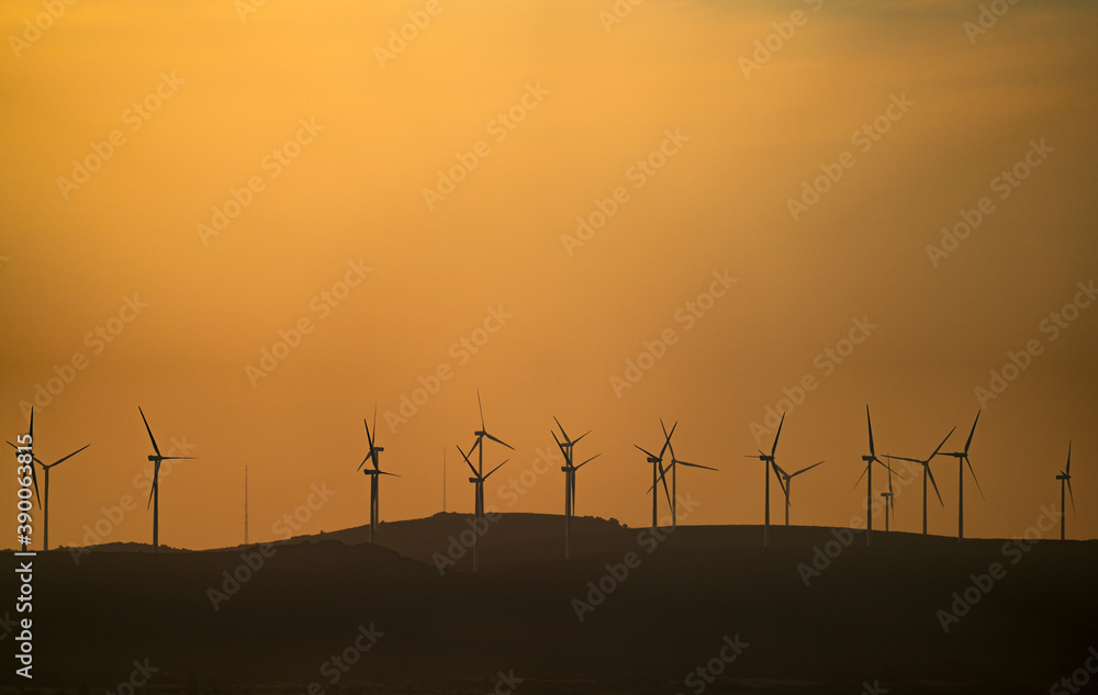 Obraz premium Windmills over the horizon with orange sky