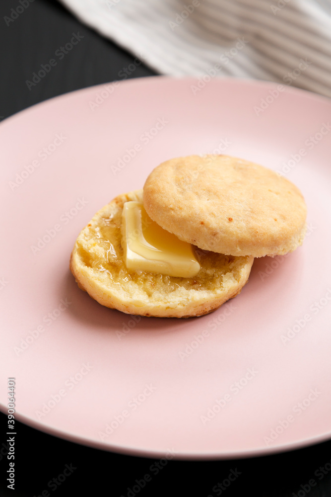 Homemade Flaky Buttermilk Biscuit on a pink plate on a black surface, low angle view.
