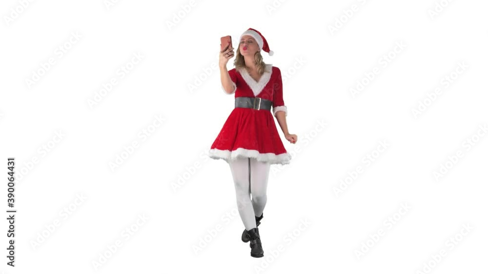 Modern Santa Claus girl walking and taking selfie photos kissing and waving at cellphone. Full length isolated on white background. Modern Santa Claus girl walking and taking selfie photos kissing and waving at cellphone. Full length isolated on white background.