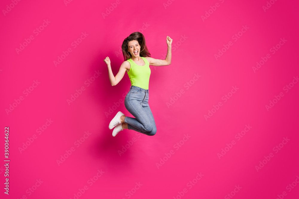 Full body photo of excited happy young girl celebrate win victory shout yeah yes jump fists hands isolated over pink color background