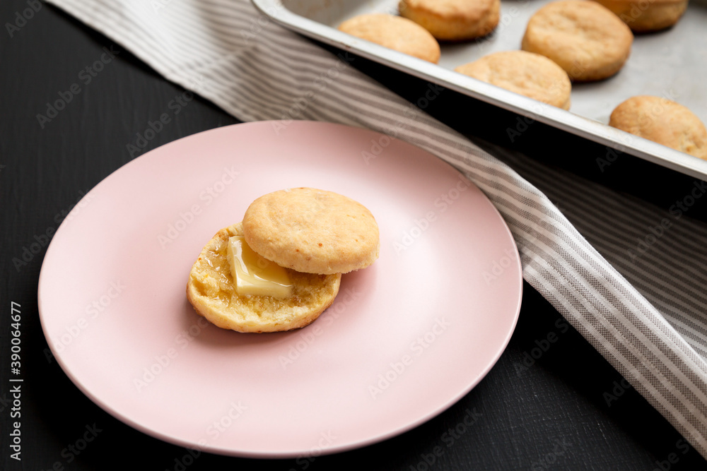 Homemade Flaky Buttermilk Biscuits on a pink plate on a black background, low angle view.