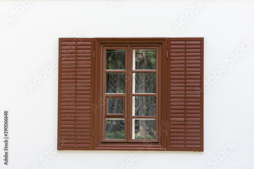 Window with brown wooden shutters and white wall