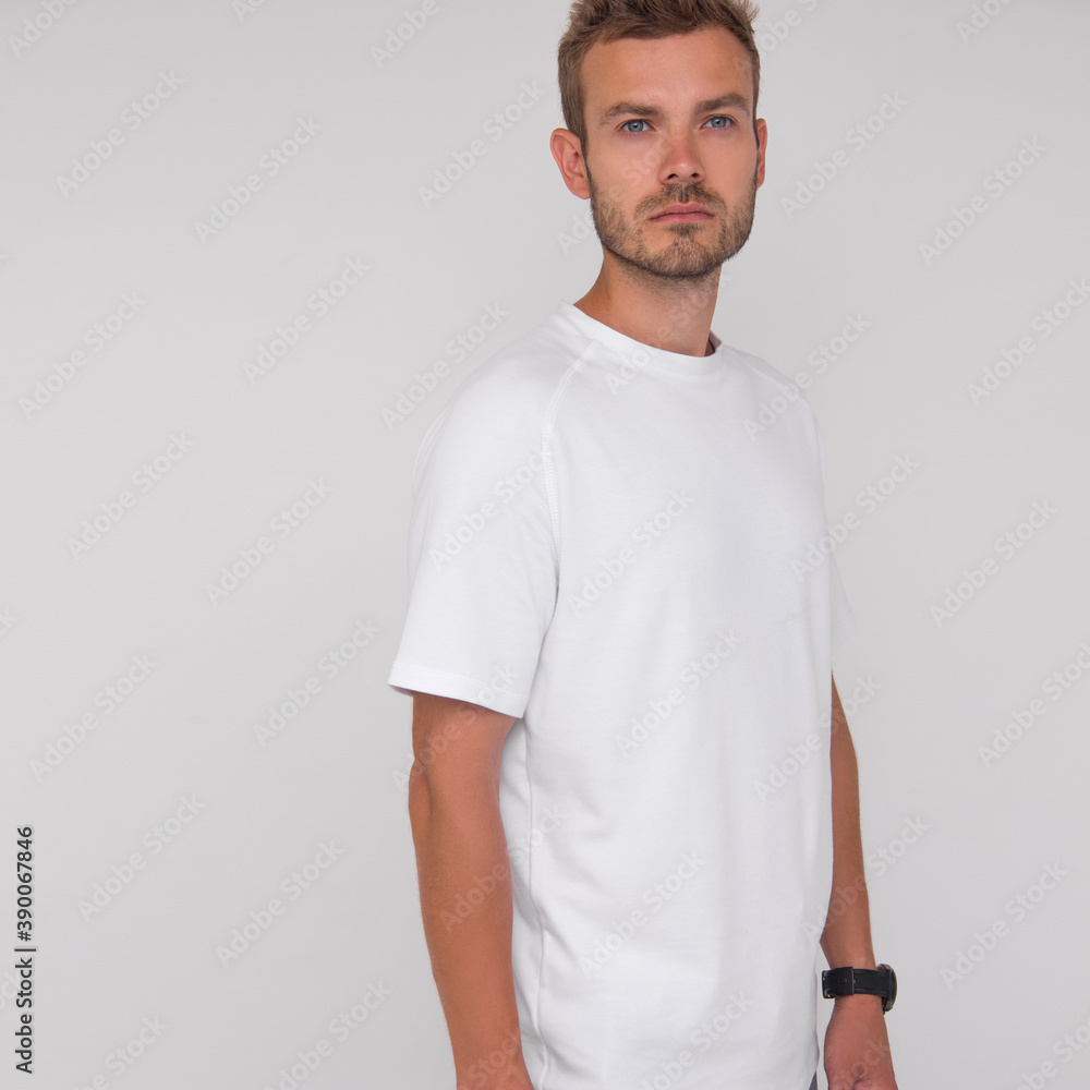 young stylish male doctor in white t-shirt is standing in profile and smiling on the white wall background. medical concept. free space , mockup young stylish male doctor in white t-shirt is standing in profile and smiling on the white wall background. medical concept. free space , mockup