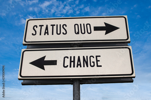 Status quo vs change. White two street signs with arrow on metal pole with word. Directional road. Crossroads Road Sign, Two Arrow. Blue sky background.
