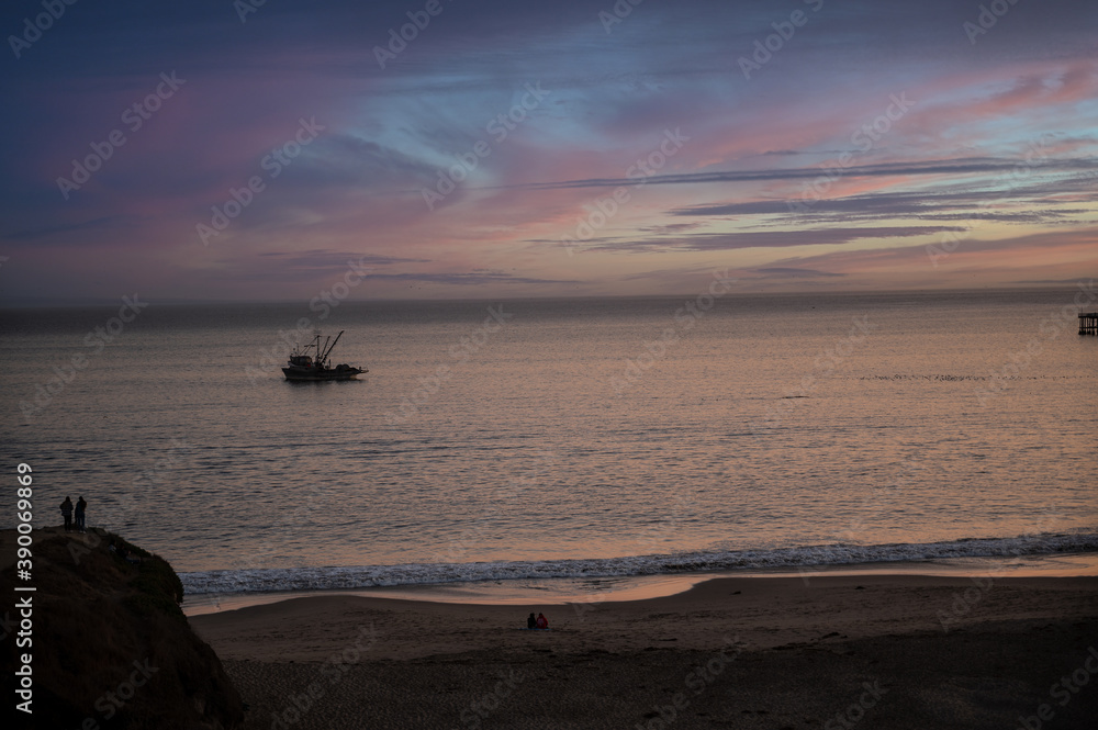 Sunset at ocean beach with fishing boat