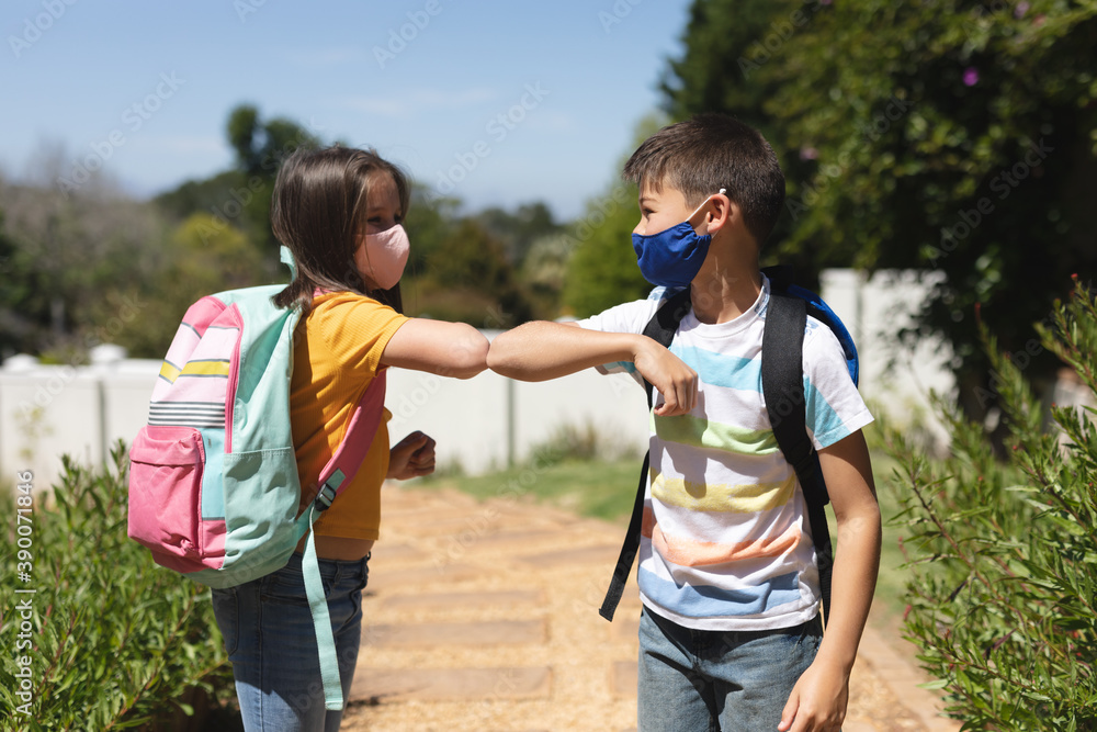 Caucasian boy and girl wearing face masks greeting on their way to school by touching elbows Caucasian boy and girl wearing face masks greeting on their way to school by touching elbows