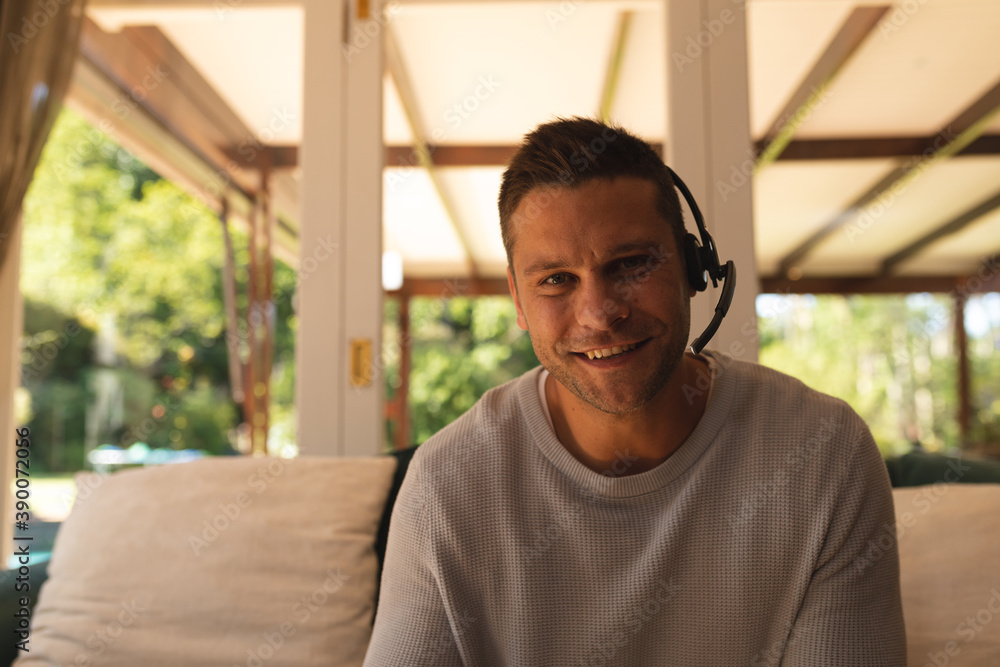 Portrait of caucasian man working from home wearing a phone headset sitting in living room and smili Portrait of caucasian man working from home wearing a phone headset sitting in living room and smili